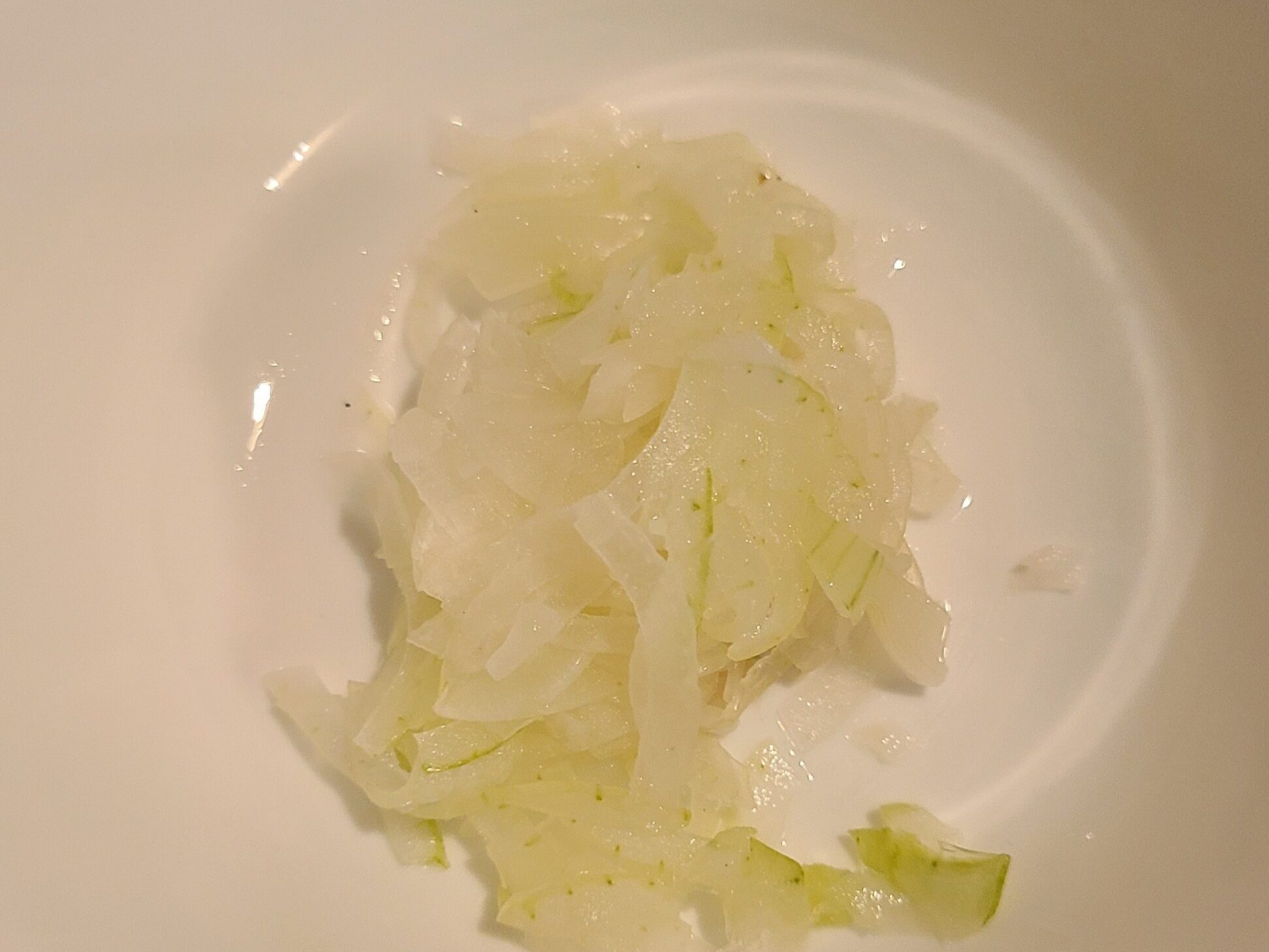 白いお皿の中に、レンジで加熱されたスライスされた玉ねぎが入っている様子。