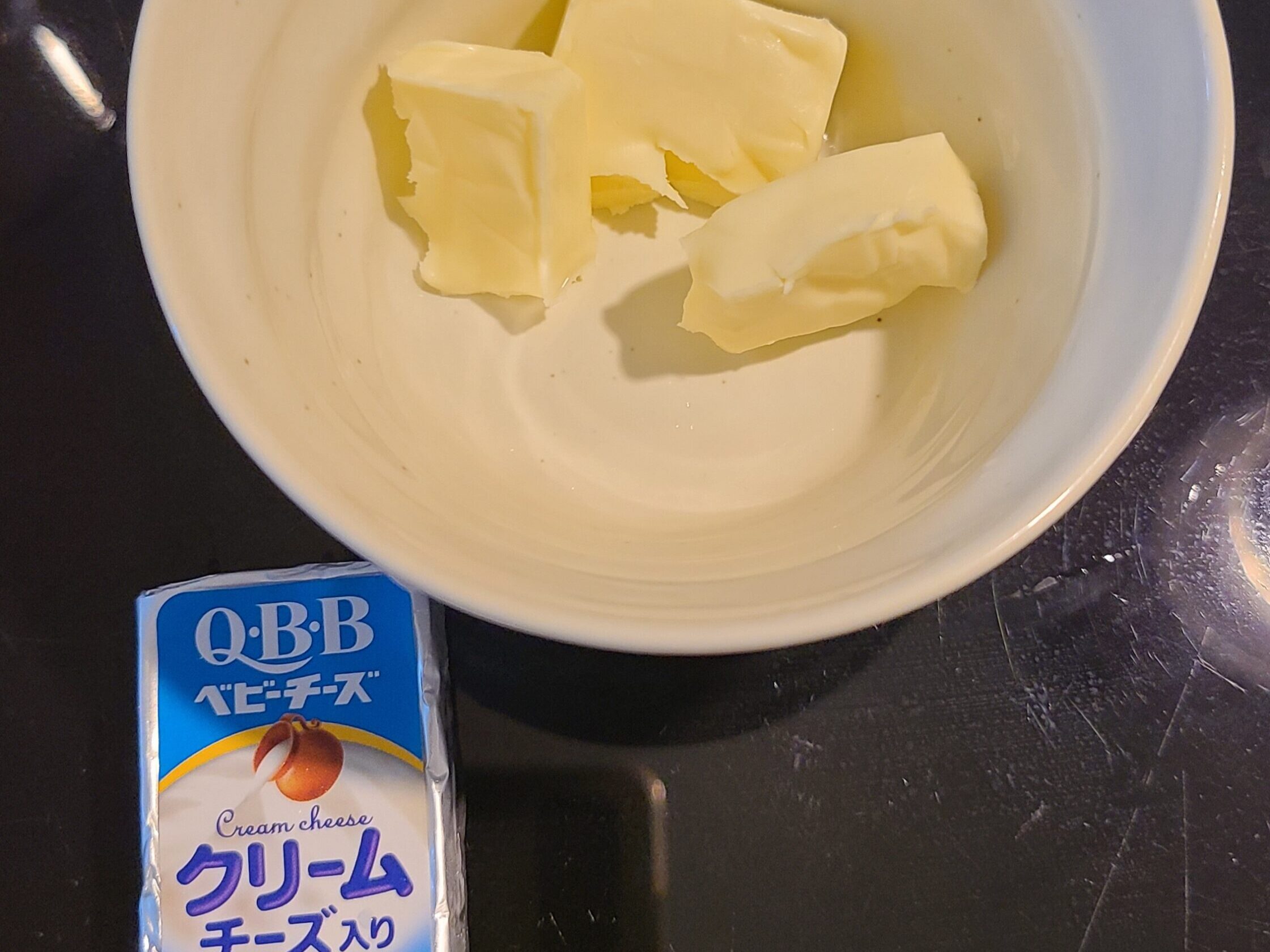 QBBベビーチーズが割れて白いカップに入っている様子と、一個のQBBベビーチーズクリーム入りの写真。