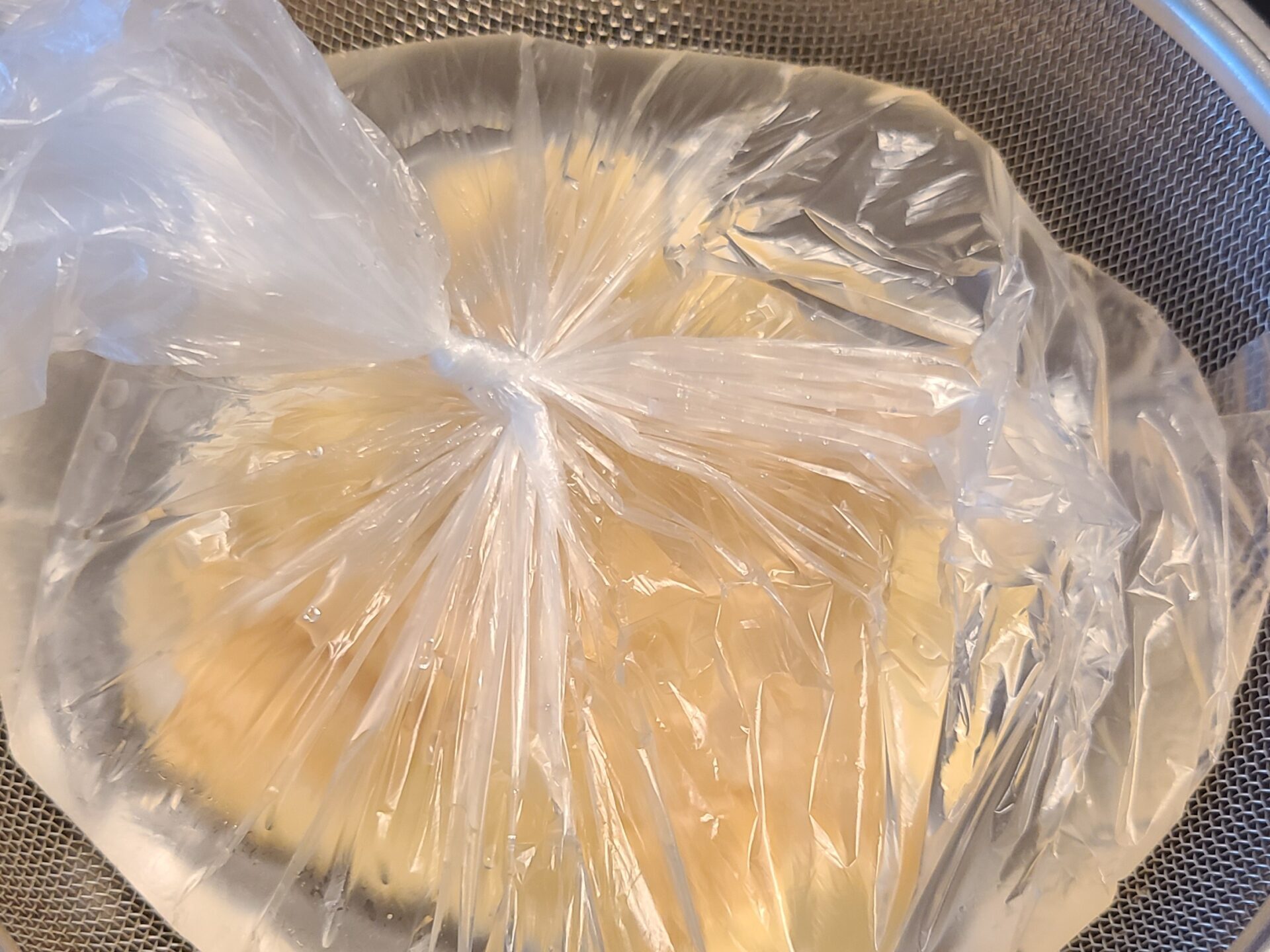 クッキングペーパーで包んだヨーグルトの上に、水が入ったビニール袋を重しにして水切りしている様子。