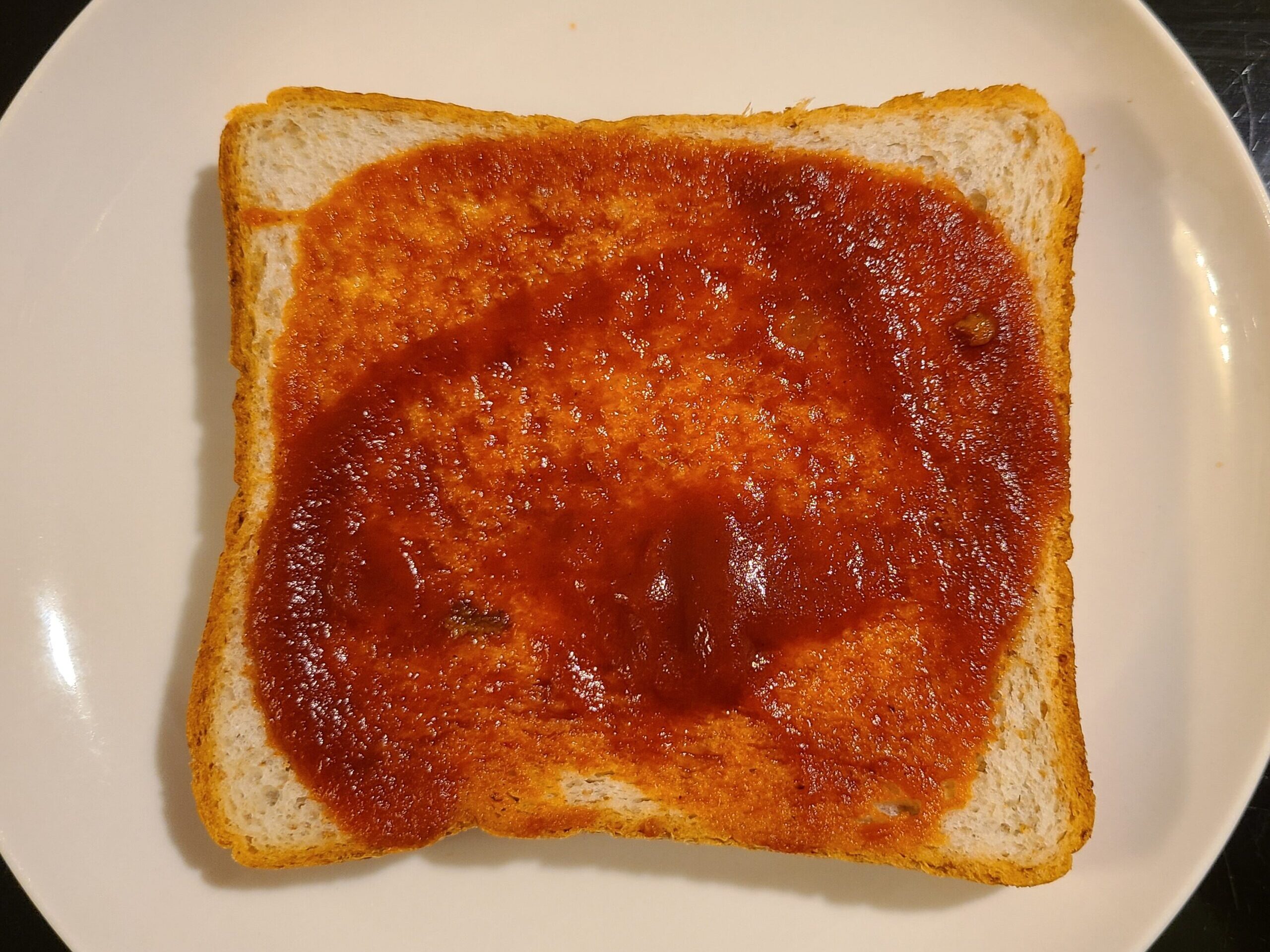 トマトソースが塗られた、白い丸いお皿の上の食パンの写真。