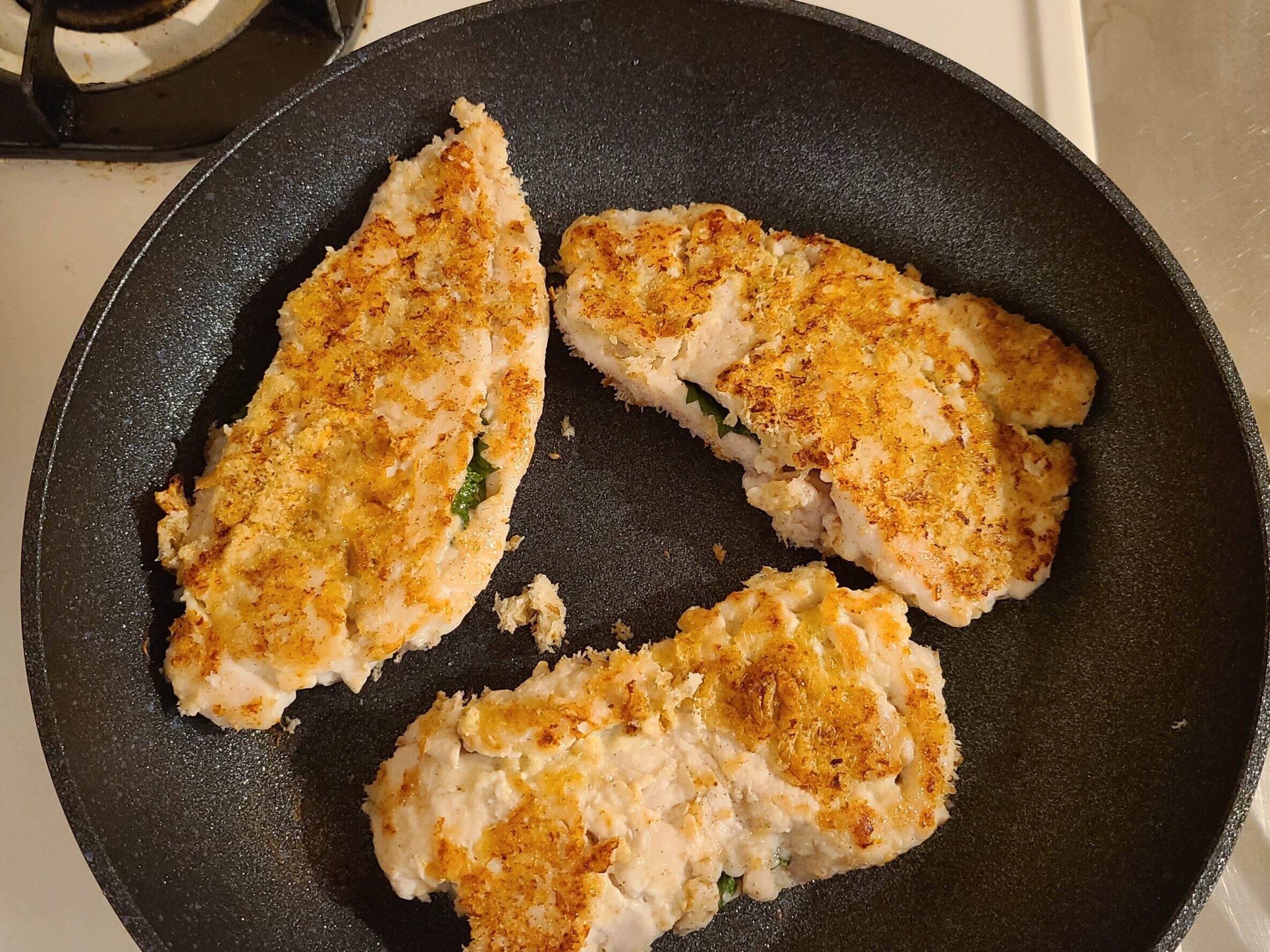 ちきんかつ3つをフライパンでこんがり焼いている様子。