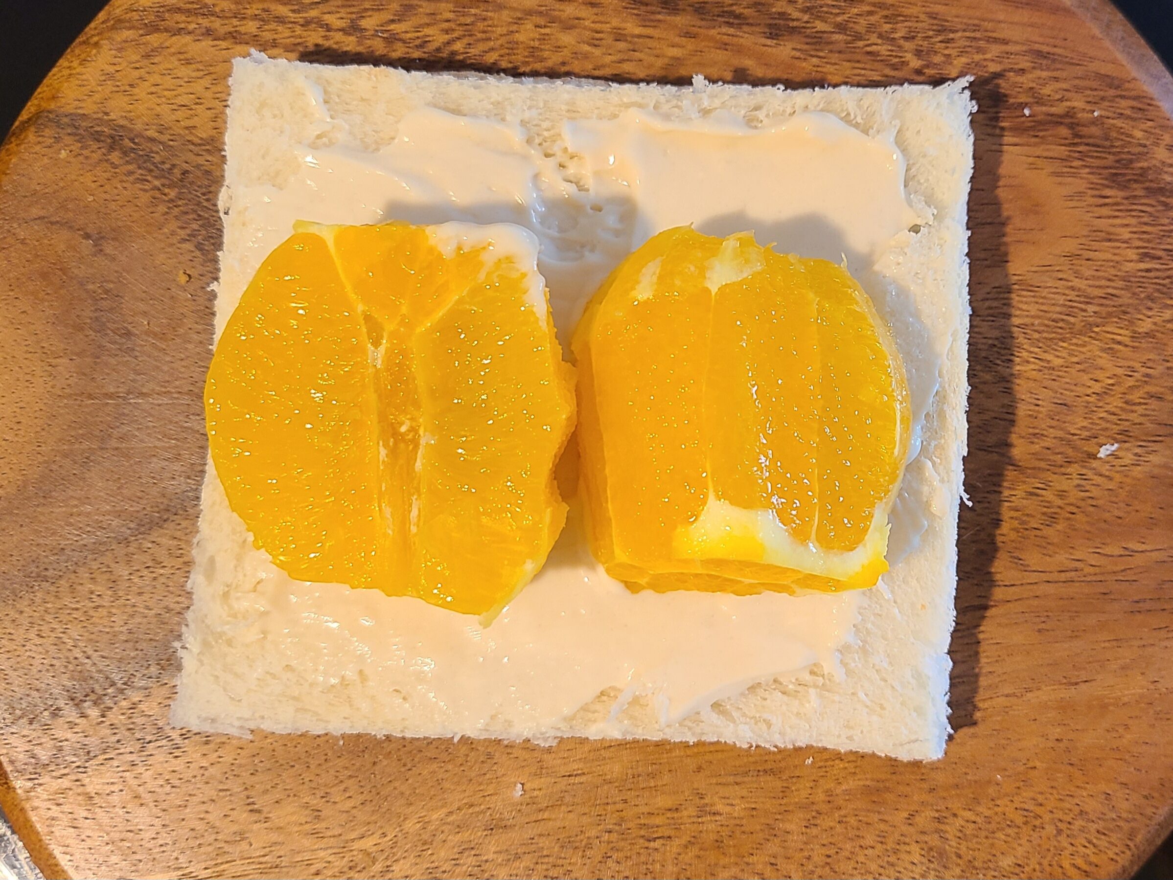食パンにヨーグルトクリームを塗り、その上に半分にカットしたオレンジを乗せた写真