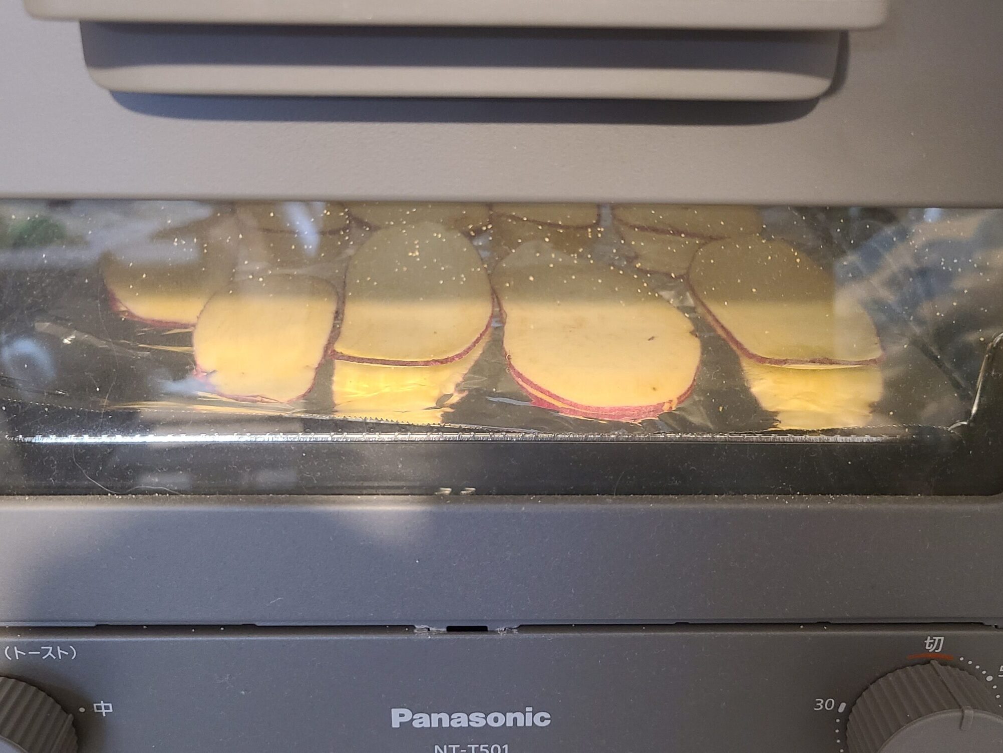 天板にアルミホイルを敷き、その上にスライスしたさつまいもを並べ、トースターに入れた写真