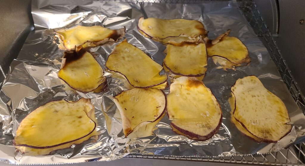 アルミホイルの上にこんがり焼かれたさつまいもチップスが並んでいる写真