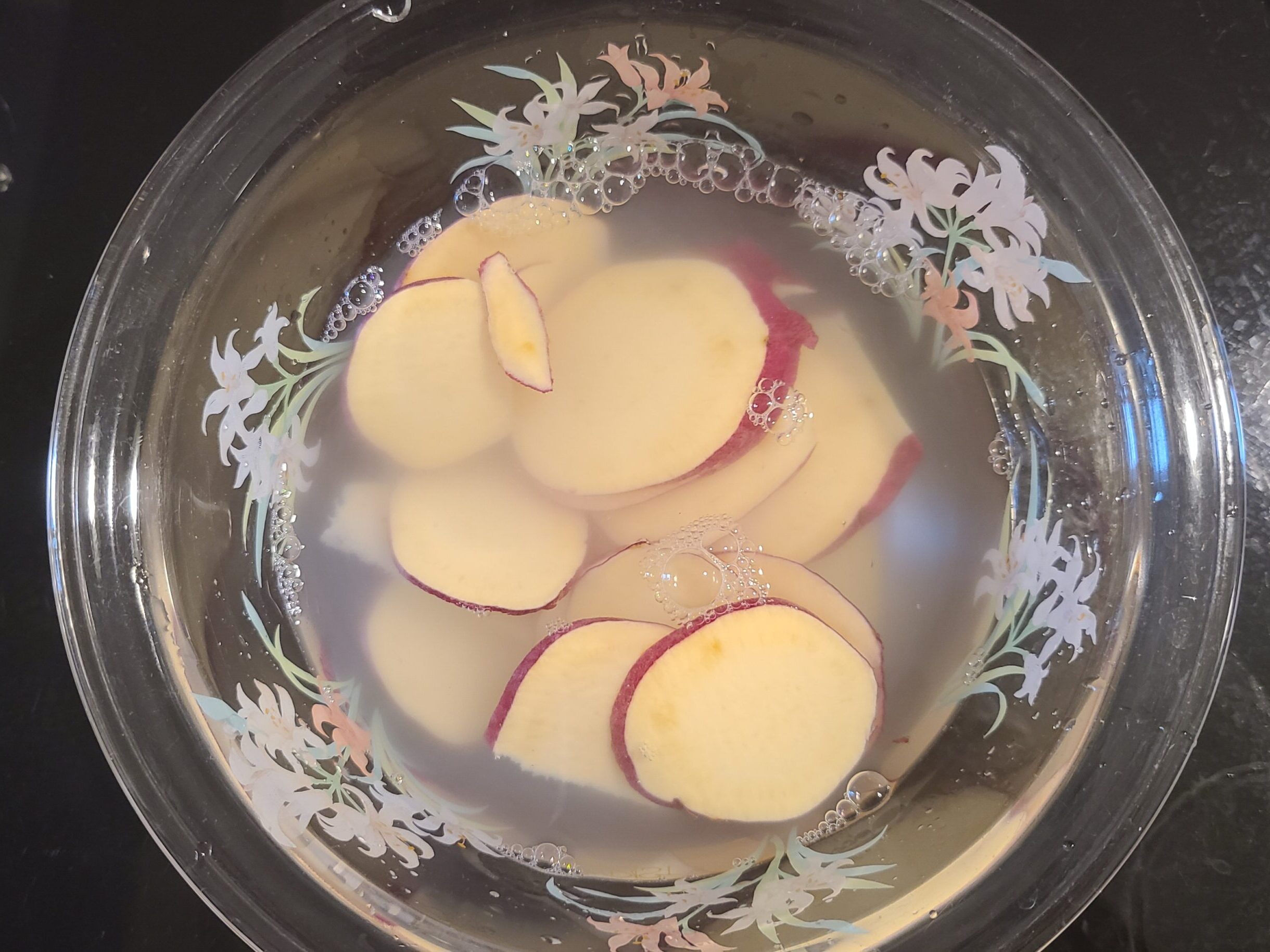 水の入っているガラスのボウルにさつまいもを浸している様子