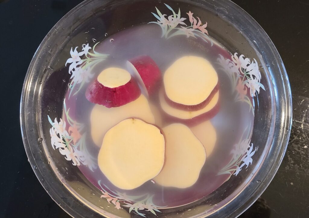 水が入ったボウルにカットされたさつまいもを入れ、あくぬきしている写真