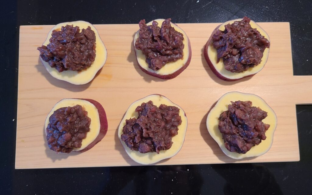 カッティングボードの上に、６個のあんこが乗ったカットされたさつまいもが乗っている写真