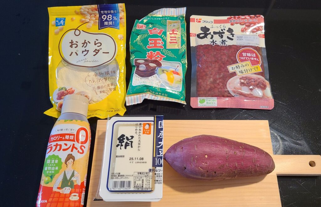 いきなり団子の材料。おからパウダー、白玉粉、小豆の水煮、ラカントS、絹豆腐、さつまいもがテーブルに載っている写真